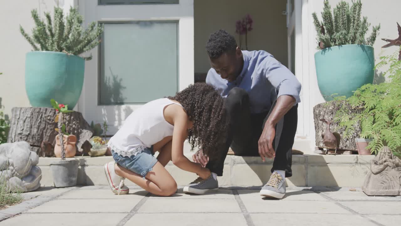 chica afroamericana atando los zapatos de su padre