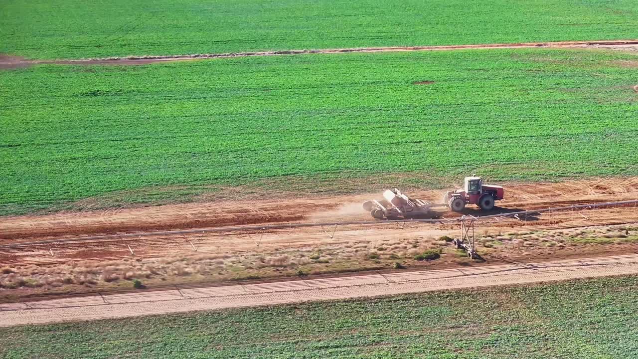 관개 장비 의 길을 따라 작업하는 트랙터와 작은 도로 그레이더