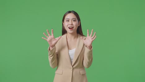 una mujer de negocios asiática mostrando gestos manos palma diciendo wow y sonriendo en el estudio de pantalla verde