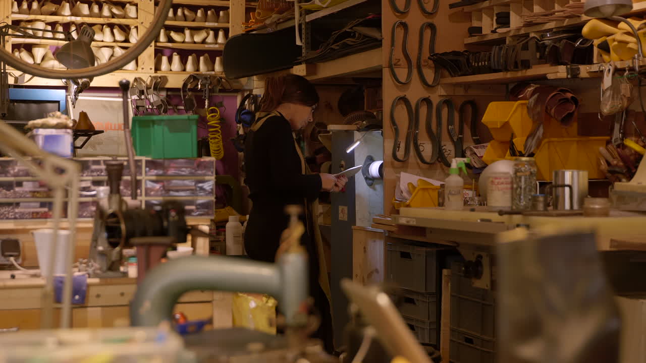 작업장 연마 기계를 사용하여 신발 밑창을 형성하는 여성 제화공