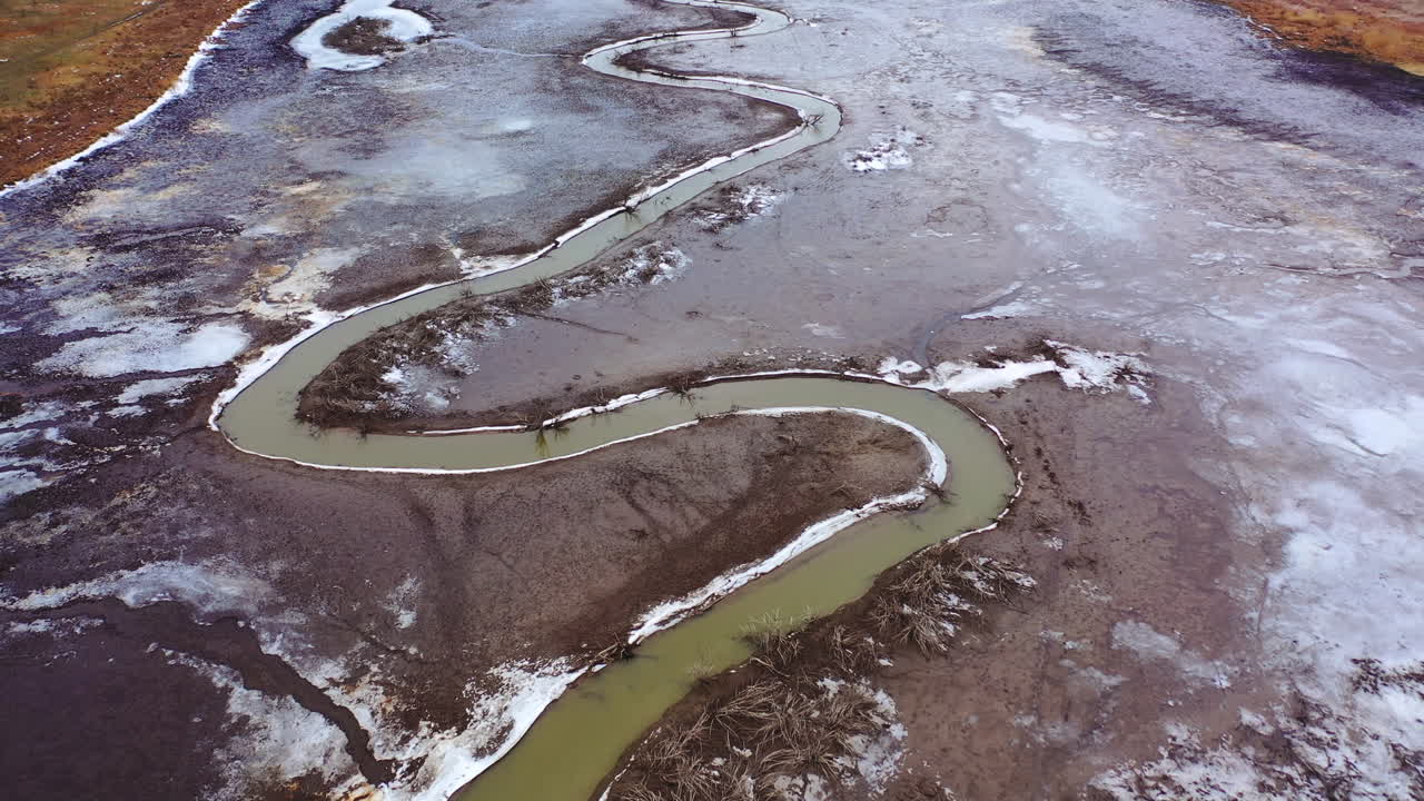 Muddy background. Dirty narrow stream of dried river. Ecological disaster. Natural problems in the world. Muddy water in tortuous river. Top aerial view.