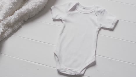 video of white baby grow and white furry rug with copy space on white background