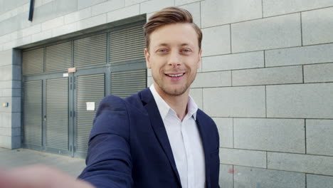 Businessman-waving-at-camera-on-street.-Worker-talking-on-video-chat-outdoors