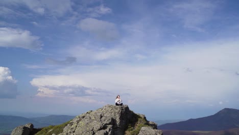 on the summit of botev peak in bulgaria’s stara planina mountains, a young woman meditates in a yoga pose. the tranquil setting reflects inner peace, balance, and connection to nature
