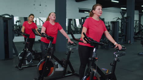 grupo de mujeres atléticas haciendo entrenamiento de estiramiento en la rutina de bicicleta estacionaria giratoria en el gimnasio en interiores