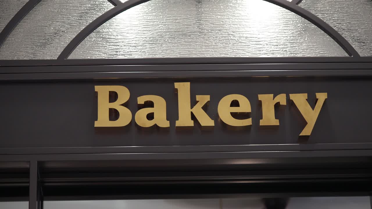 Cartel de panadería con letras doradas y ventana de cristal texturizado