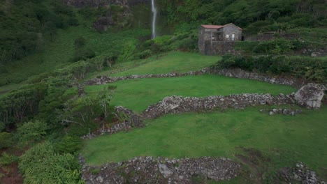 revela una toma aérea de la cascada do poço do bacalhau con la casa