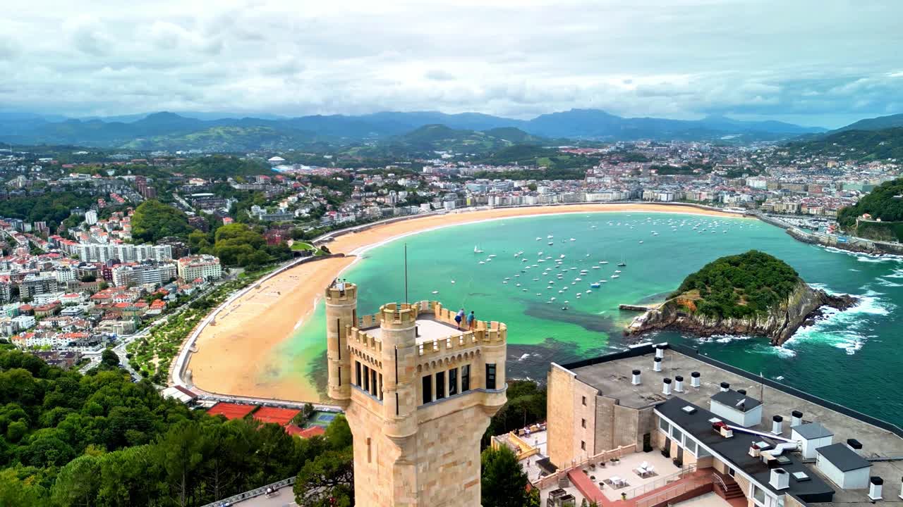 Veduta panoramica dalla cima di una collina dello storico Torreón sul Monte Igueldo con vista sulla Baia della Concha, sul paesaggio urbano di San Sebastián e sulla spiaggia sabbiosa sotto nuvole suggestive nei Paesi Baschi, Spagna.