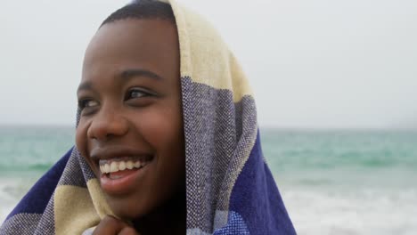 front view of african american woman wrapped in blanket on the beach 4k