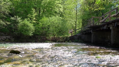 Kristallklares-Wasser,-Das-In-Einem-Sanften-Bach-Unter-Einer-Brücke-Fließt