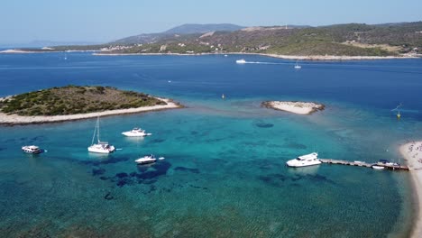 Menschen-Entspannen-Sich-In-Der-Blauen-Lagune-Der-Insel-Veliki-Budikovac-Mit-Katamaranen,-Yachten-Und-Booten,-Die-In-Der-Kristallklaren-Bucht-Vor-Anker-Liegen