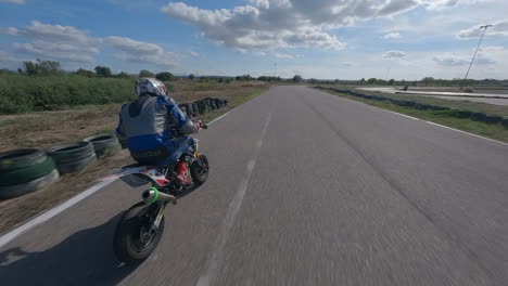 fpv drone pov chasing motorcycle racer speeding around spanish track circuit, aerial view