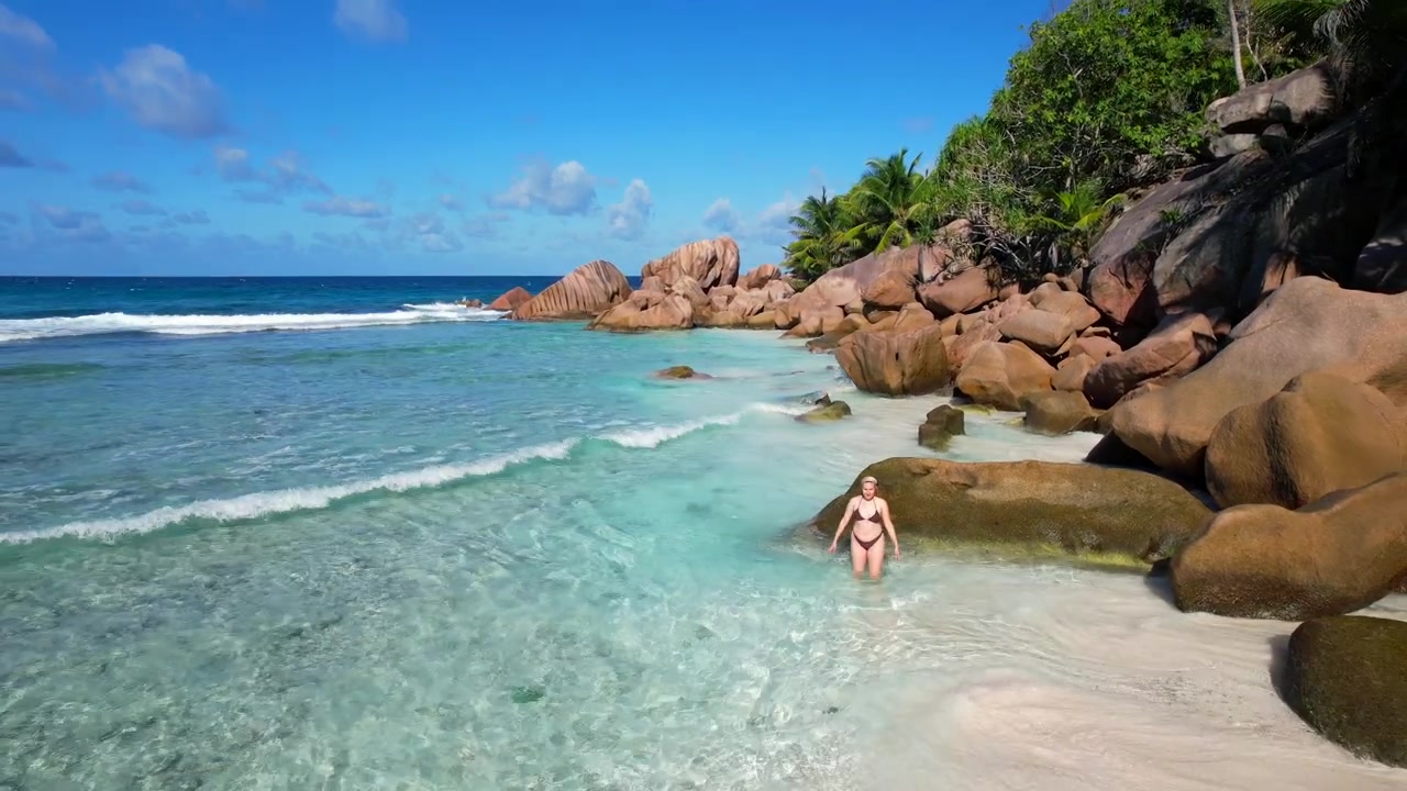 Donna posa in acqua turchese su una spiaggia tropicale delle Seychelles. Veduta aerea.