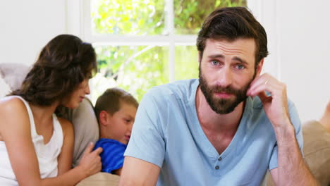 Concentrated-father-in-front-of-mother-and-son-sitting-on-a-sofa