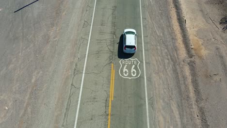 Luftaufnahme-Eines-Autos,-Das-Auf-Der-Straße-In-Ludlow,-Kalifornien,-über-Das-Schild-Der-Route-66-Fährt