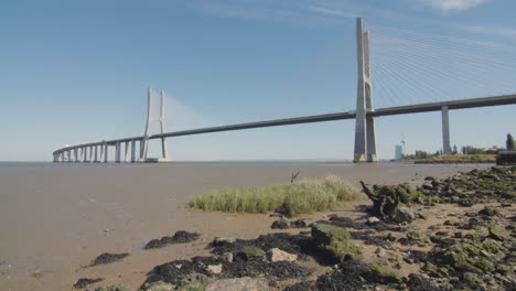 low tide beach in lisbon, portugal. vasco da gama bridge in the distance