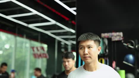 a man performs dumbbell squats in a well-lit gym, showcasing determination and strength