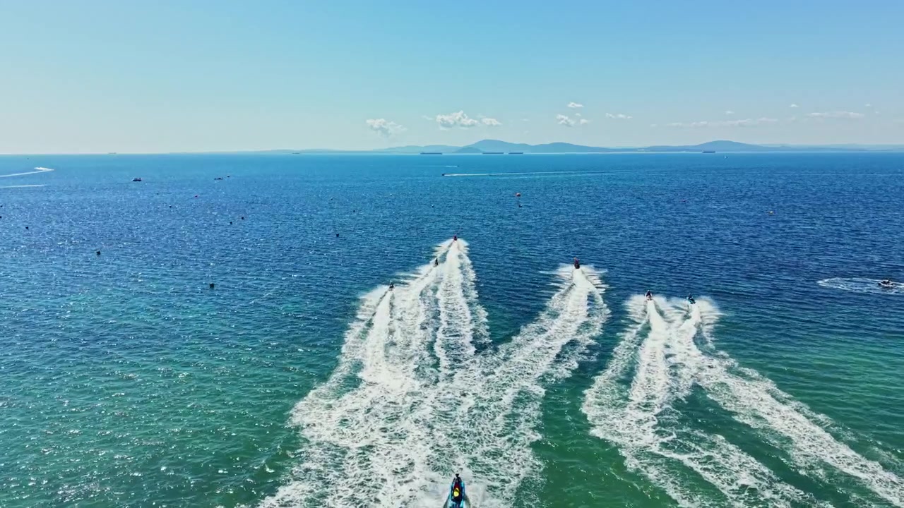 Gara di jet ski su acque cristalline sotto un cielo sereno, vicino alla costa, con molti piloti e imbarcazioni in una giornata di sole.