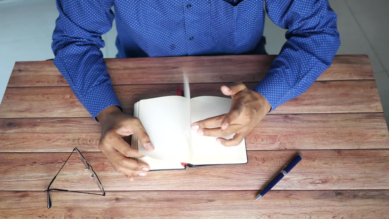 persona leyendo un cuaderno en una mesa de madera