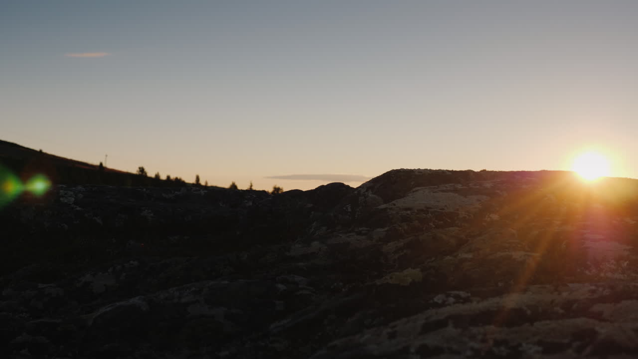 una mujer con botas de trekking camina por las piedras, el sol naciente ilumina bellamente las piernas y viaja