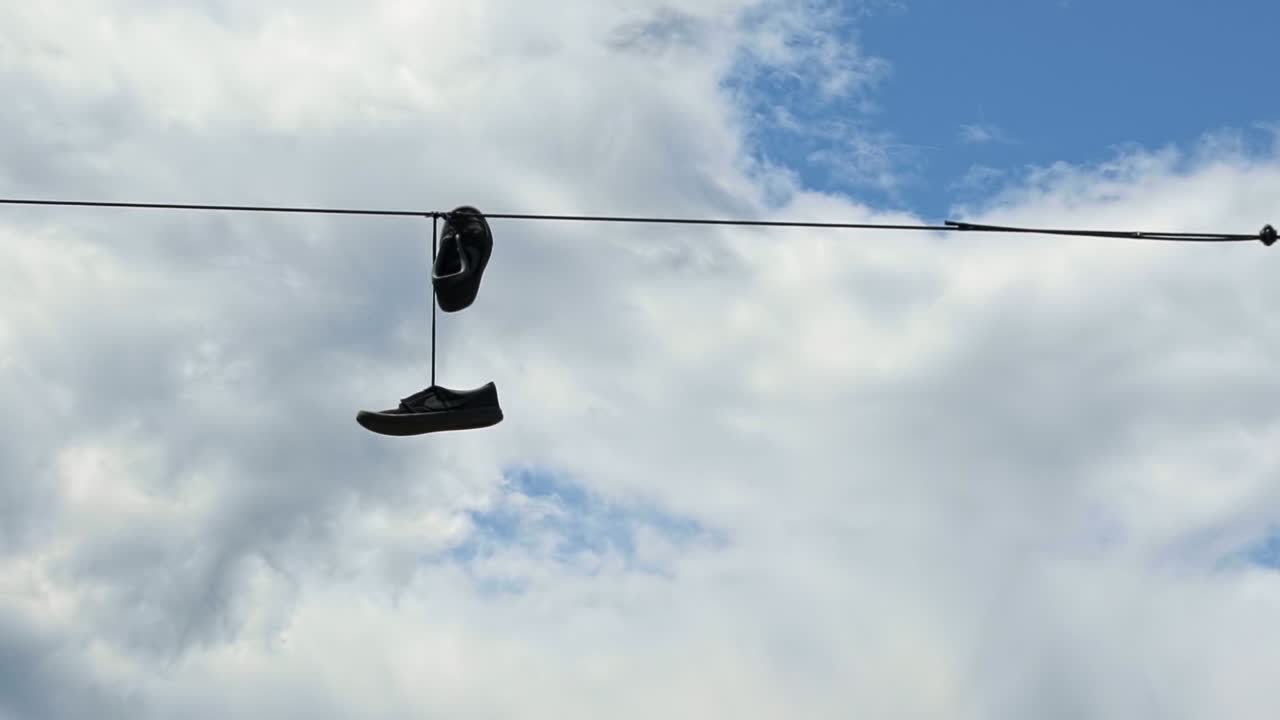 Close up of a pair of shoes tied together dangling from a power line in Seattle, Washington on a warm sunny summer day
