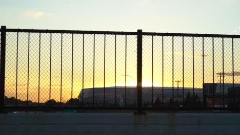 sunset peaking through fence on bridge
