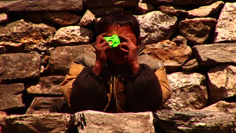 niño nepalés pretendiendo tomar fotos con un juguete