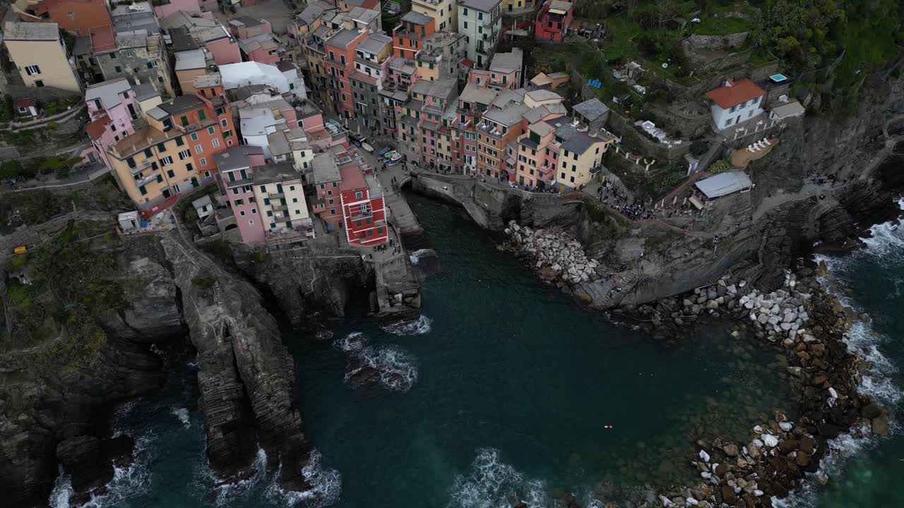 Riomaggiore, Cinque Terre, Italie : vue aérienne cinématographique du village d'en haut avec les vagues s'écrasant.