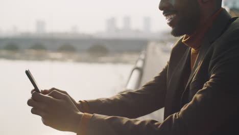 african american businessman messaging on phone in city