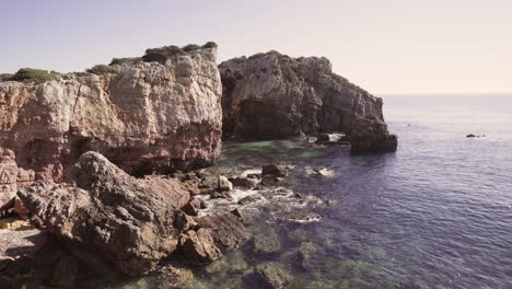 Felsen-Und-Klippen-Mit-Kristallklarem-Wasser,-Das-Sich-In-Der-Algarve-Portugal-Bewegt