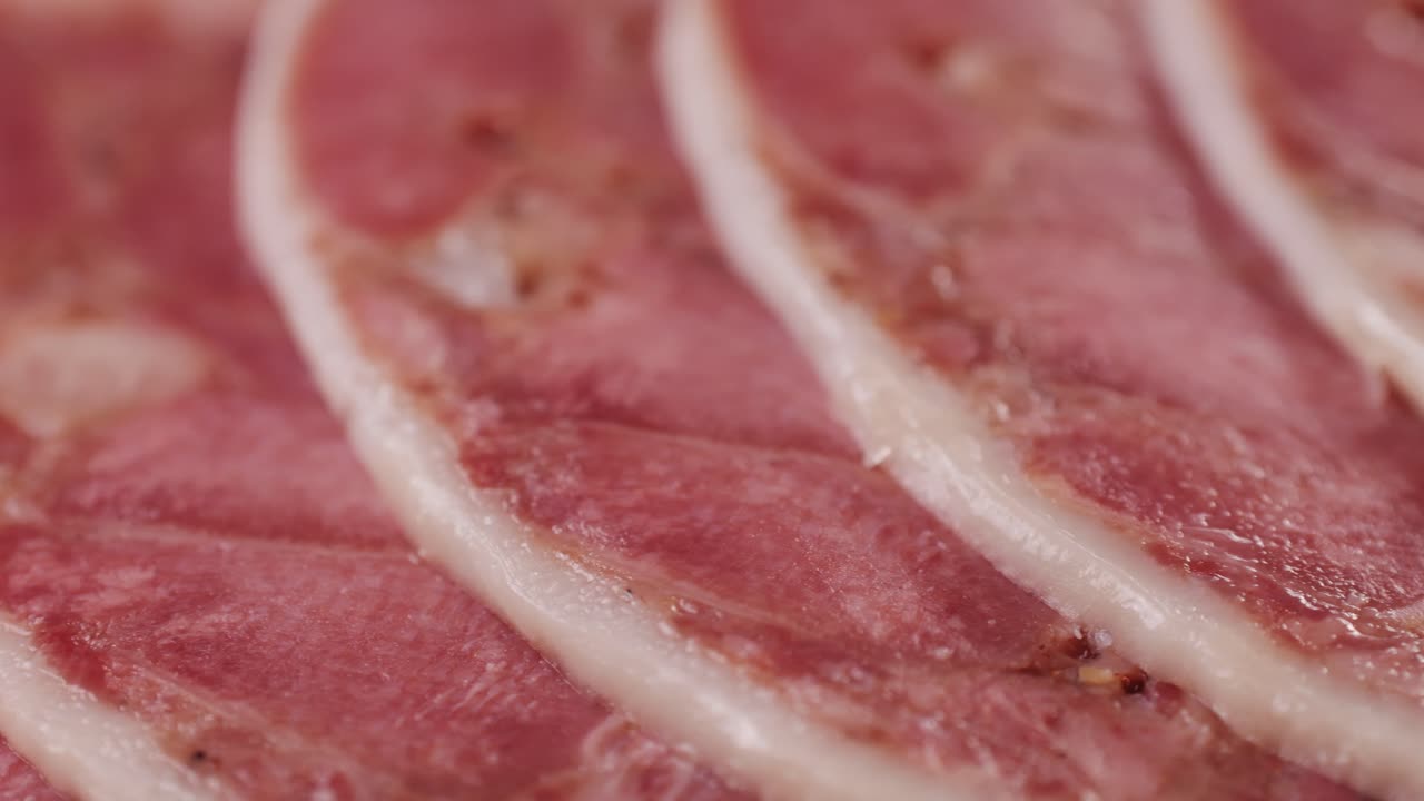 black bull sausage ham, tongue pork dry-cured sausage on a black background, traditional spanish delicatessen food, close up.