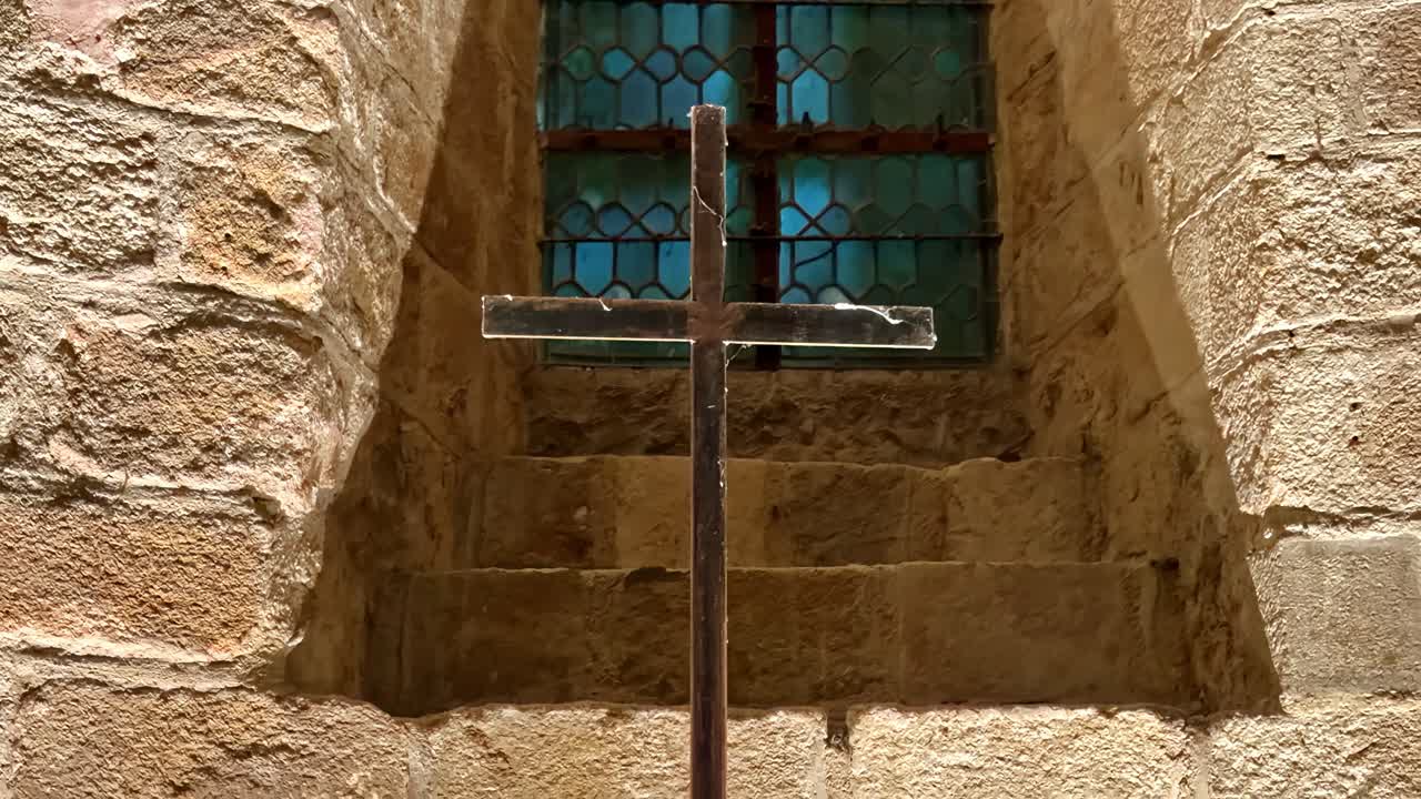 Croce in piedi davanti a una vetrata all'interno dell'Abbazia di Mont-Saint-Michel, Francia, che cattura la sacra architettura medievale e l'atmosfera storica del monastero.