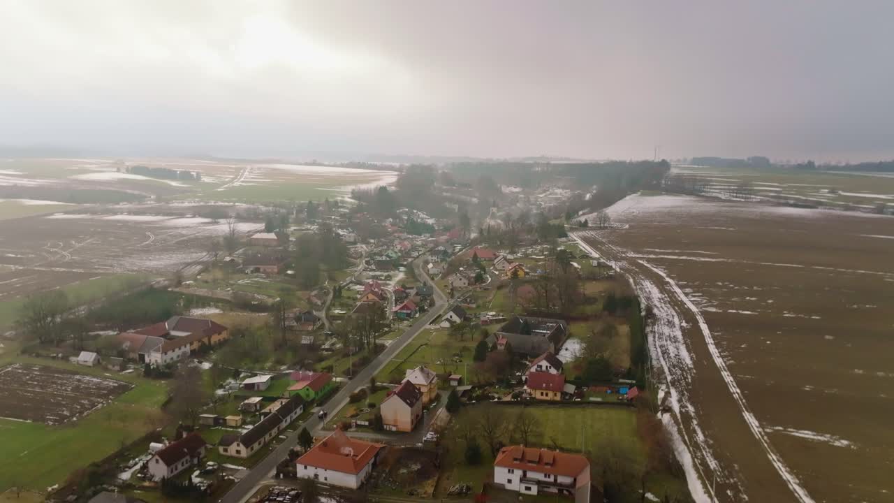 A car driving through a rural village near the beginning of spring