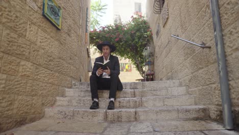 man reading a book on steps in a jerusalem alleyway