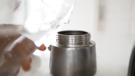 pouring fresh water into silver coffee pot for beverage preparation