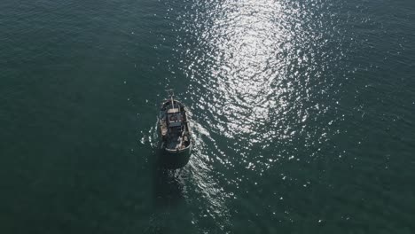 Vista-Aérea-Del-Barco-De-Pesca-En-Aguas-Poco-Profundas,-Acercándose-Al-Horizonte