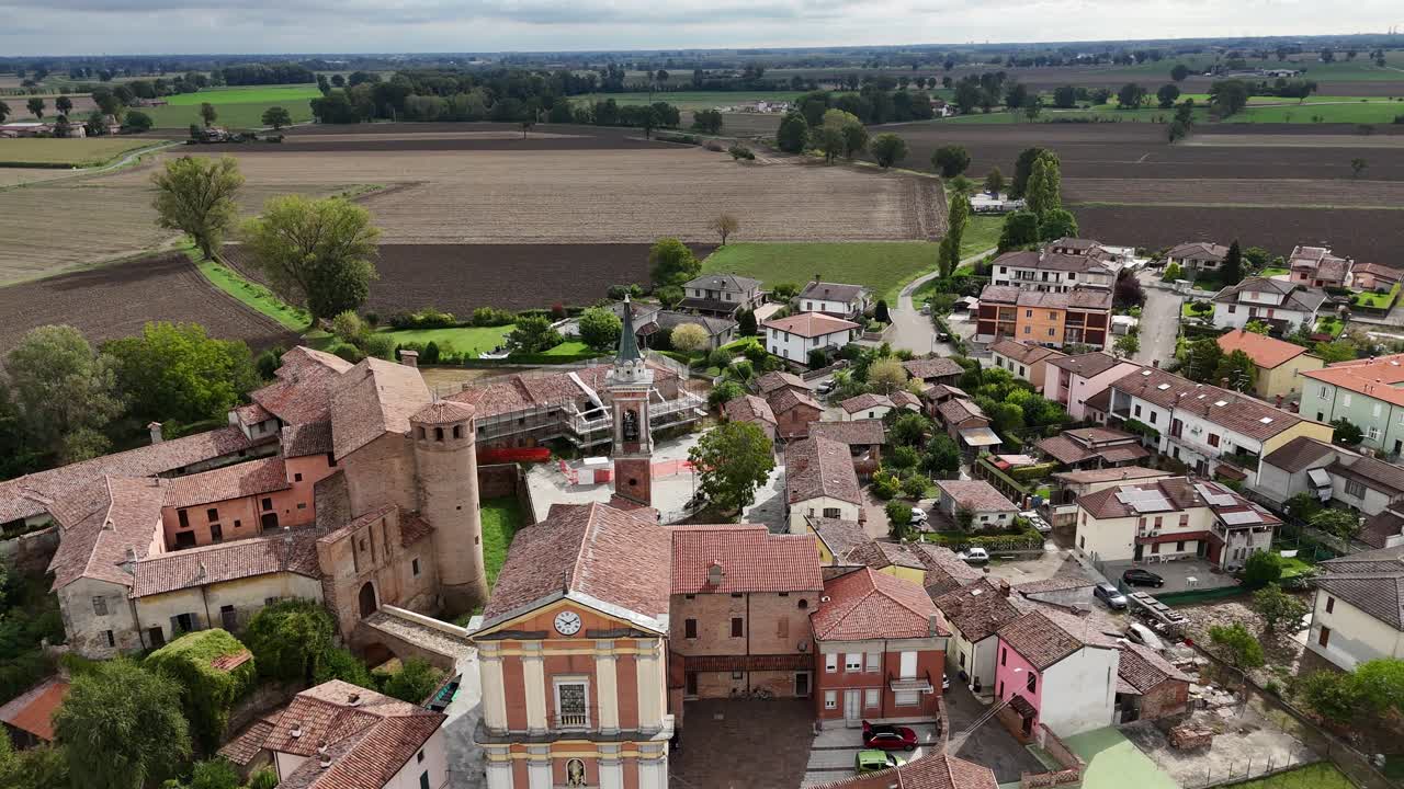 Chiesa parrocchiale e centro storico di Calendasco in Provincia di Piacenza, Emilia-Romagna, con tetti in tegole, edifici castellani vicini e la pianura agricola della Val Padana che si estende all'orizzonte