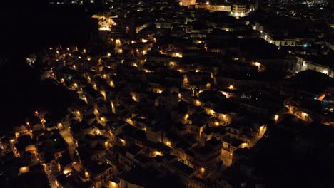 Aerial-top-down-view-of-Modica-Alta-Val-di-Noto-Sicily-Old-Baroque-Town-Rooftops-Southern-Italy-at-Night