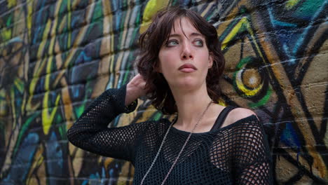 close up outdoor fashion portrait of young alternative style woman leaning against graffiti covered wall in london city street uk in real time 3