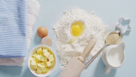 Video-of-baking-ingredients,-muffin-papers,-eggs-and-tools-lying-on-white-surface