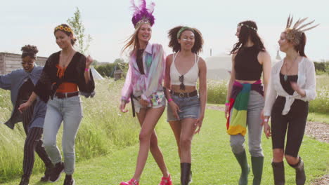 group of excited young female friends walking through music festival site