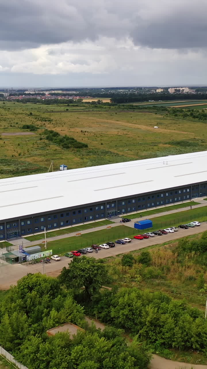 Modern industrial complex in the rural place. View from the air on commercial building in summer time. Aerial view. Vertical video