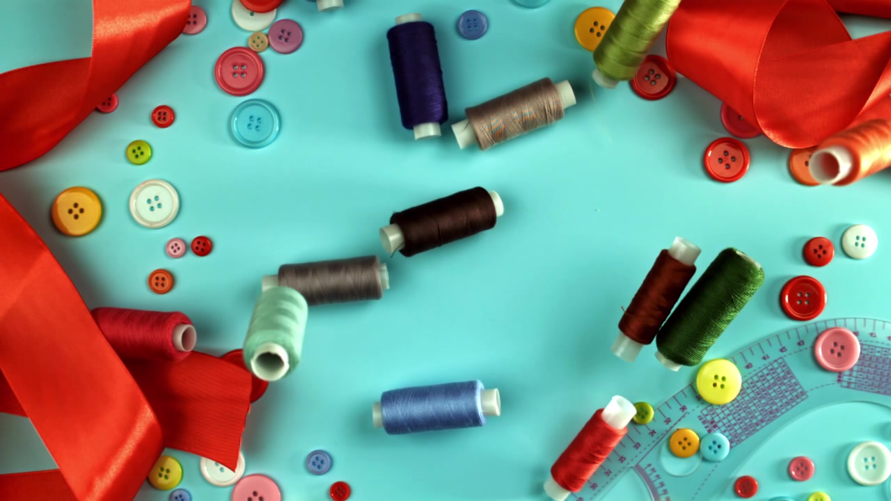 Colorful Sewing Threads Falling onto a Blue Background with Craft Supplies