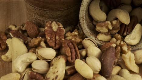 Close up macro: Healthy mixed nuts revolve on wooden board block