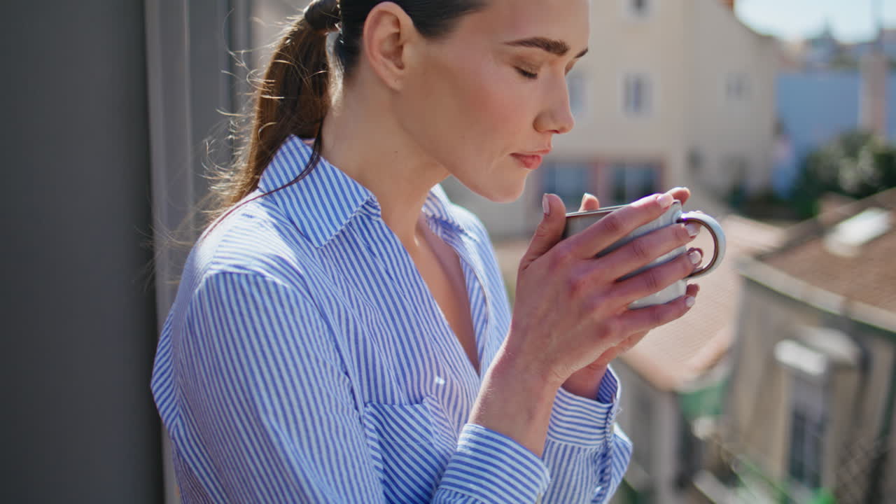 Girl hands carrying cup at sunny city view balcony closeup. Model sipping coffee