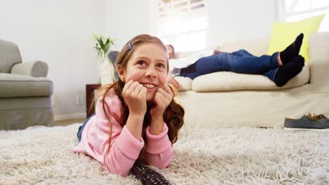 Girl watching tv lying on the rug in the living room