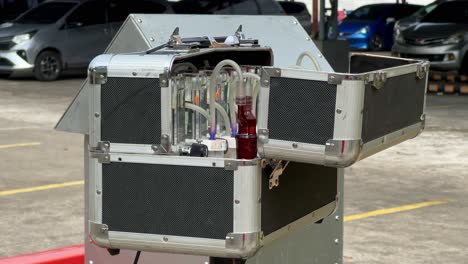 automated air sampling device deployed in an urban area, featuring laboratory-grade gas detection equipment inside an open protective case. impinger and hvas machine for air checking quality