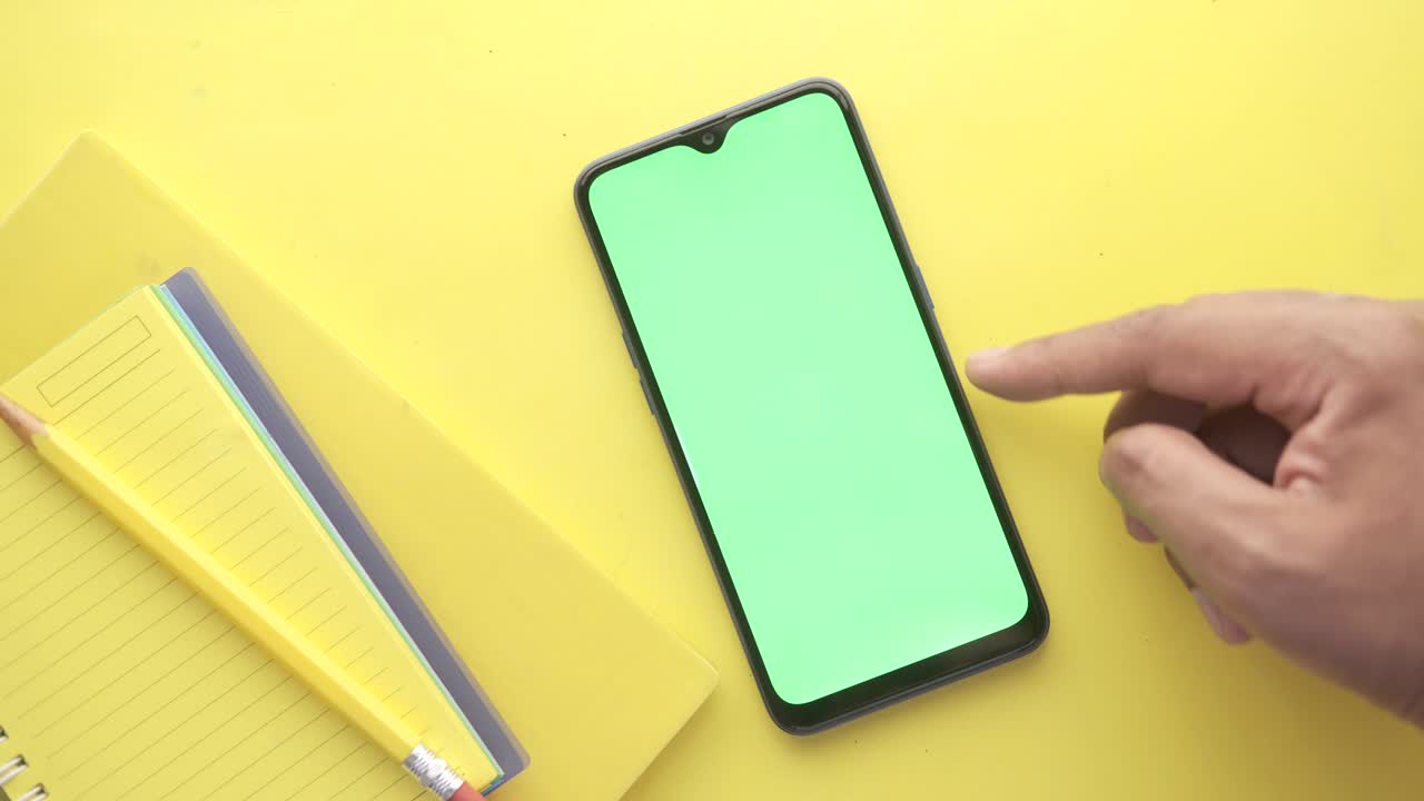 vista superior de la mano del hombre usando un teléfono inteligente sobre un fondo amarillo