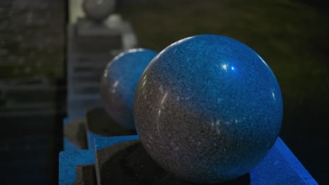 close-up view of illuminated granite spheres at night, showcasing their smooth, polished surfaces and the soft, blue lighting