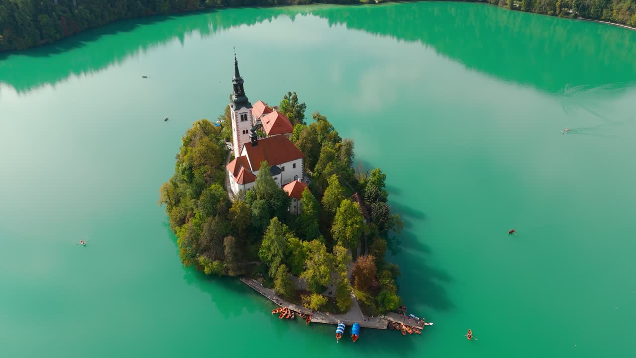 Bled Island and the Church of the Assumption over turquoise Lake Bled, slow right drone orbit